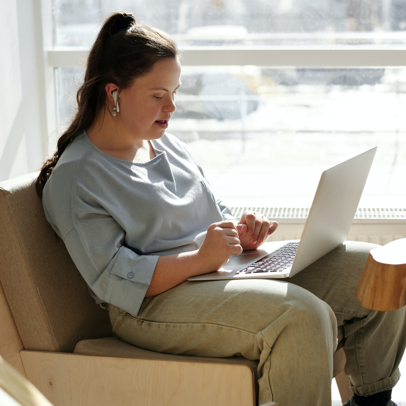 A lady wearing wireless earphones using a laptop