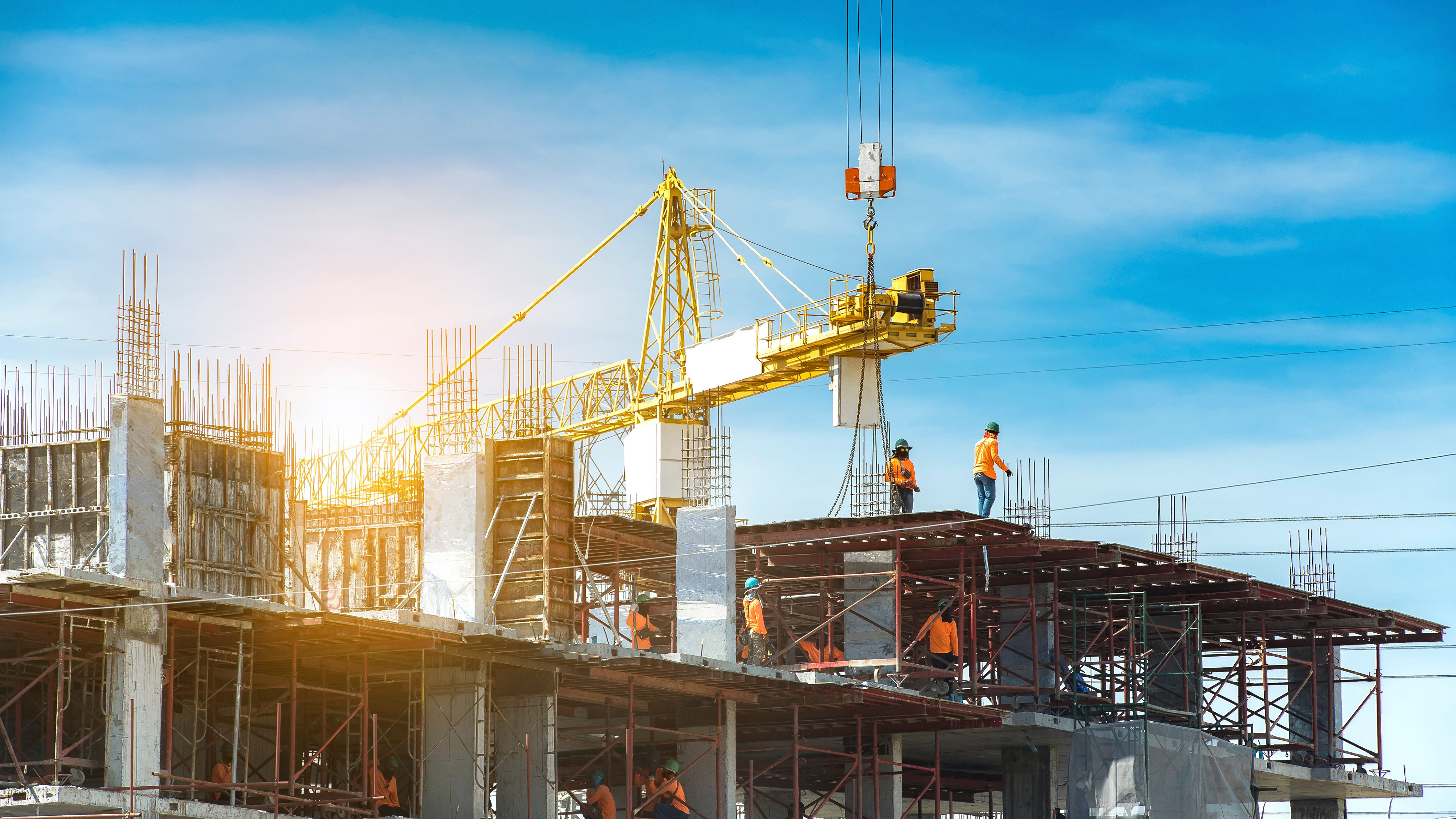 Construction site with cranes and building against blue sky background