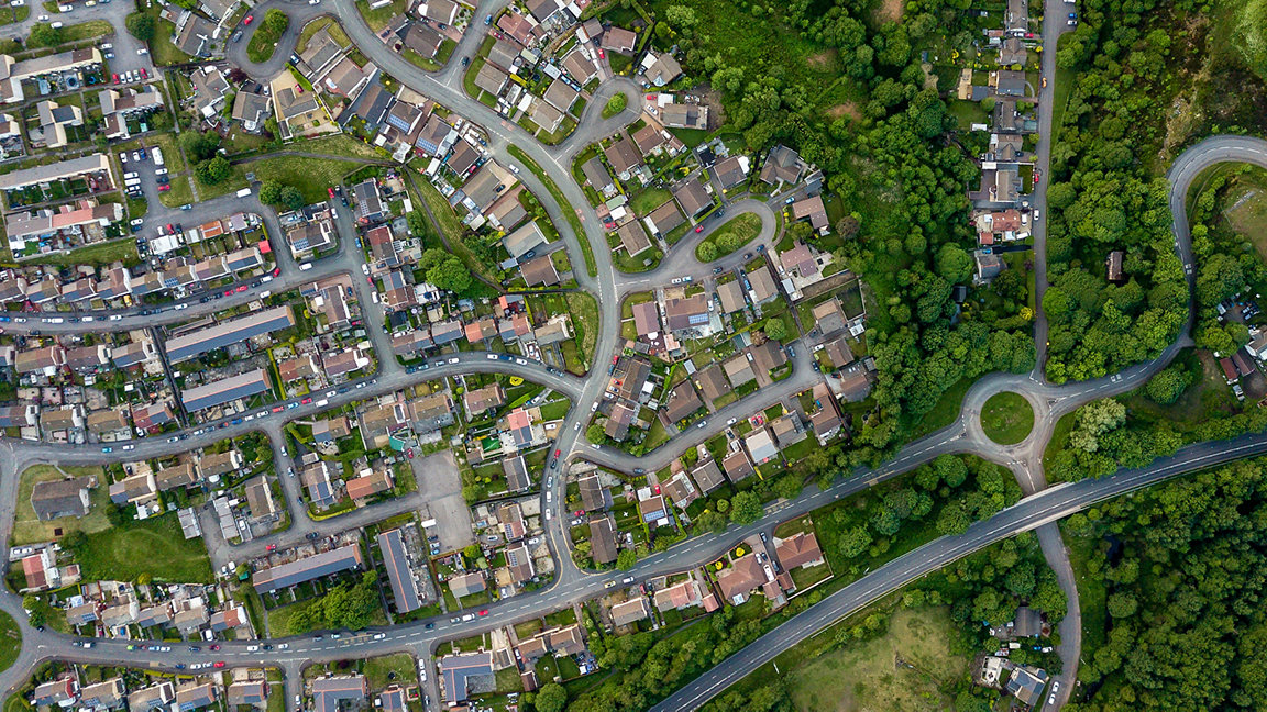 Top down aerial view of an urban area in a small town surrounded by trees and greenery