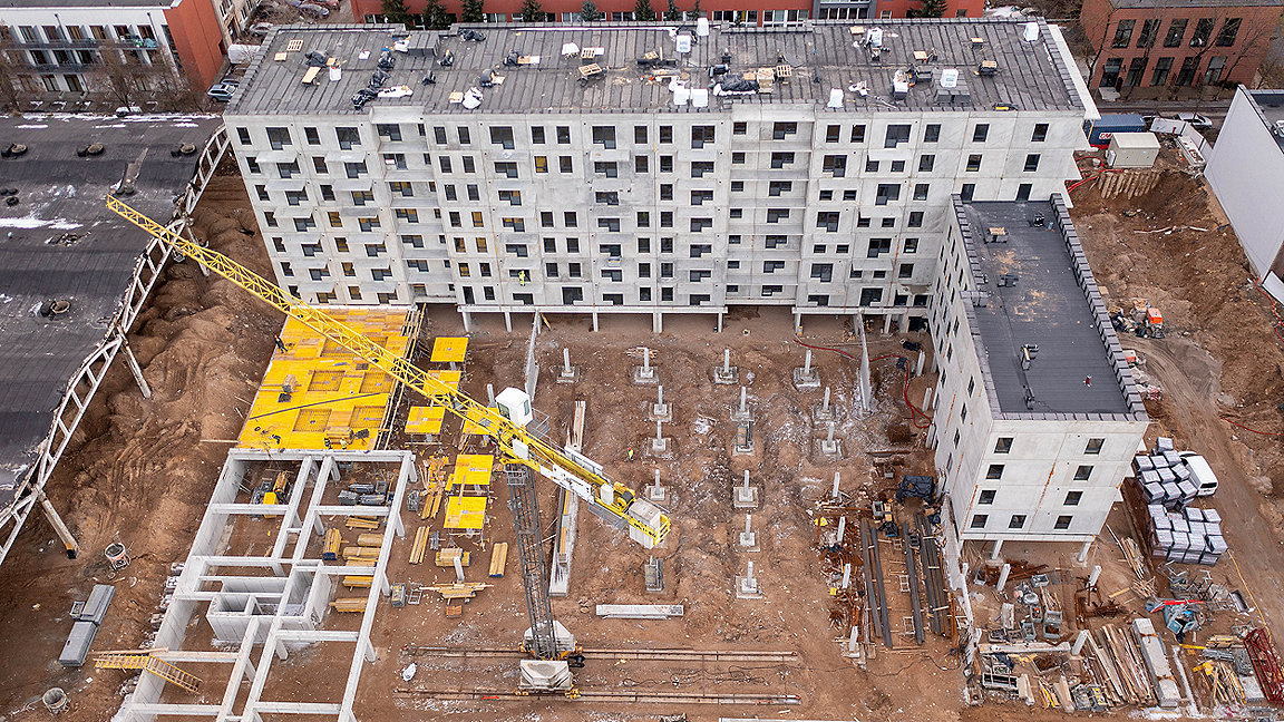 Overhead drone shot of apartment building complex under construction with crane on site