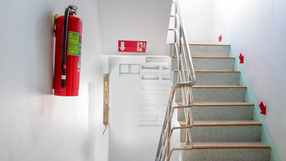 Fire extinguishers on wall next to staircase