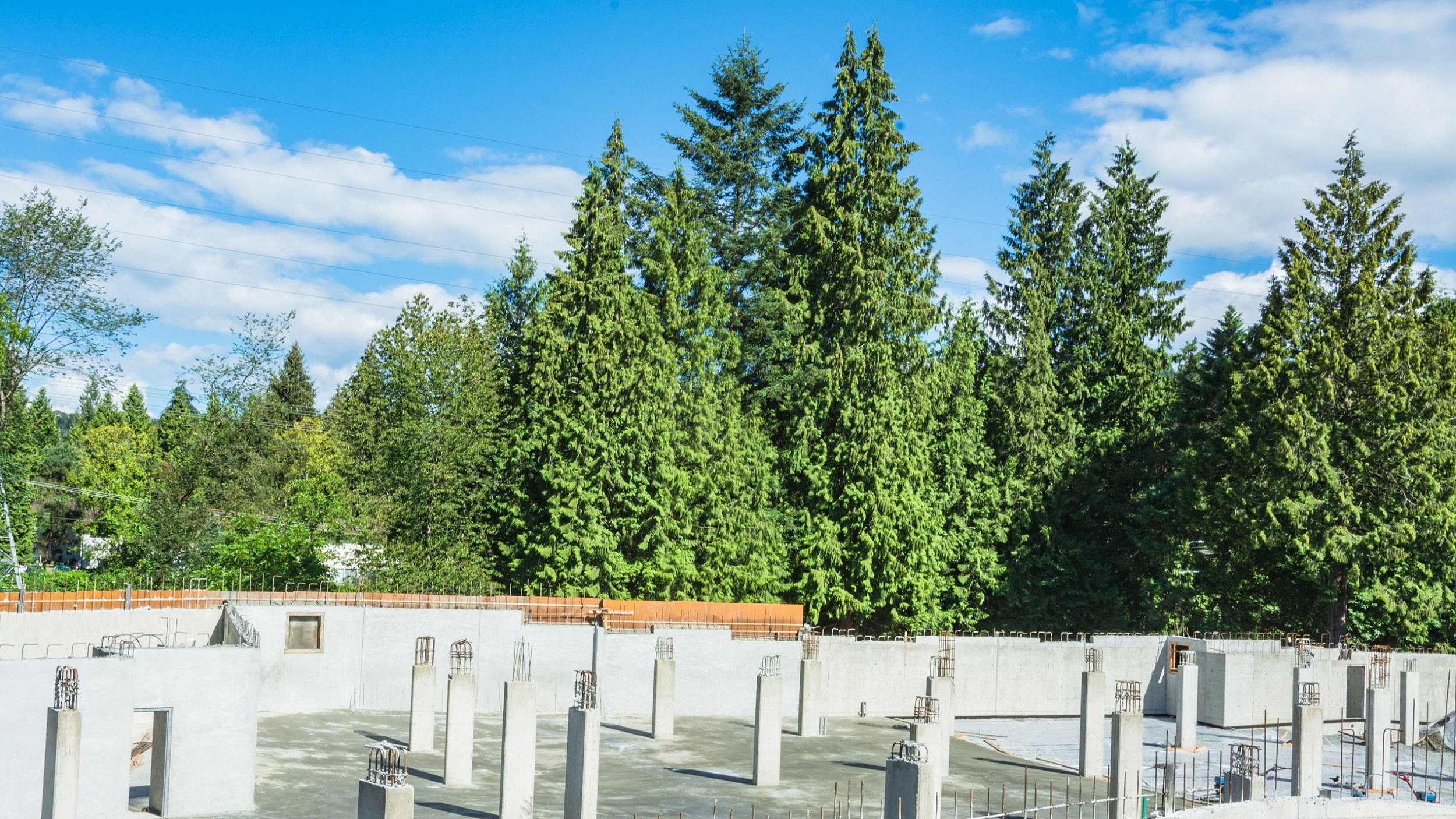 Photo of construction in progress in foreground with green trees in background
