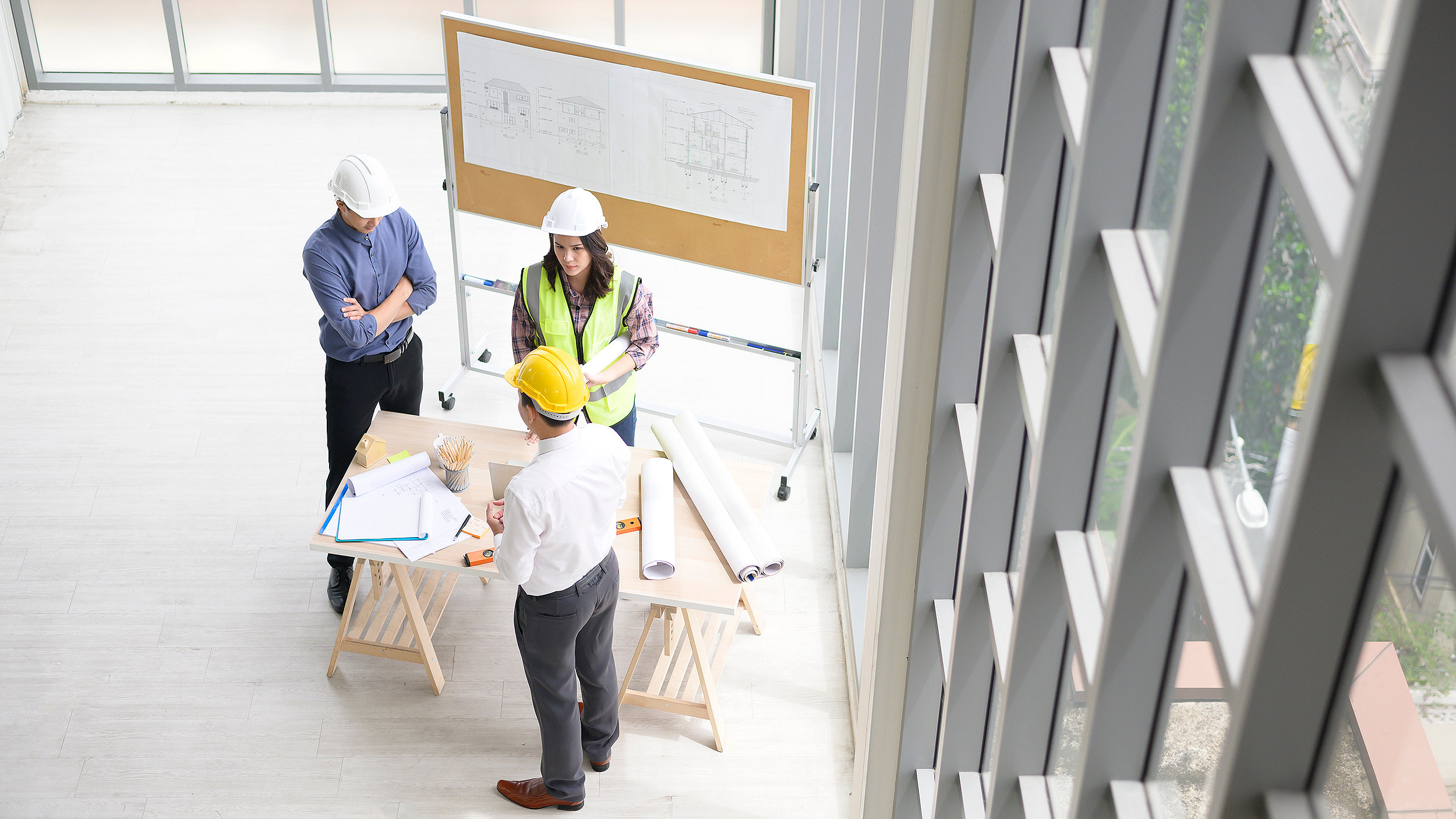 overhead photo of three construction professionals on site having a conversation