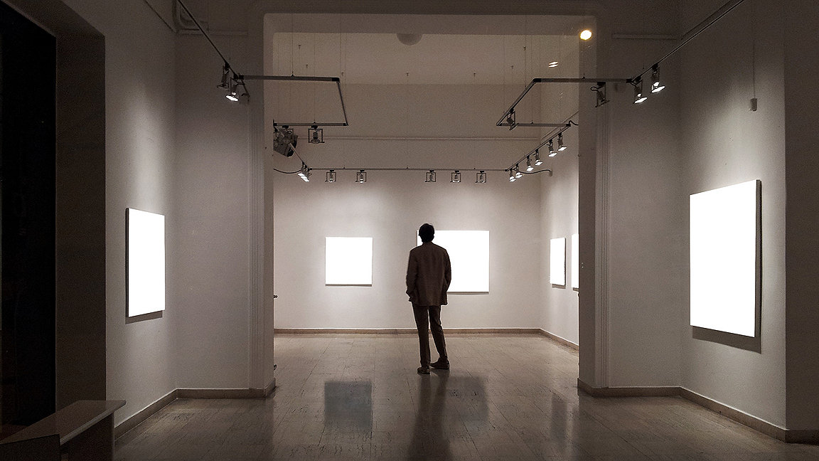 Man standing in shadow in art gallery with empty canvasses