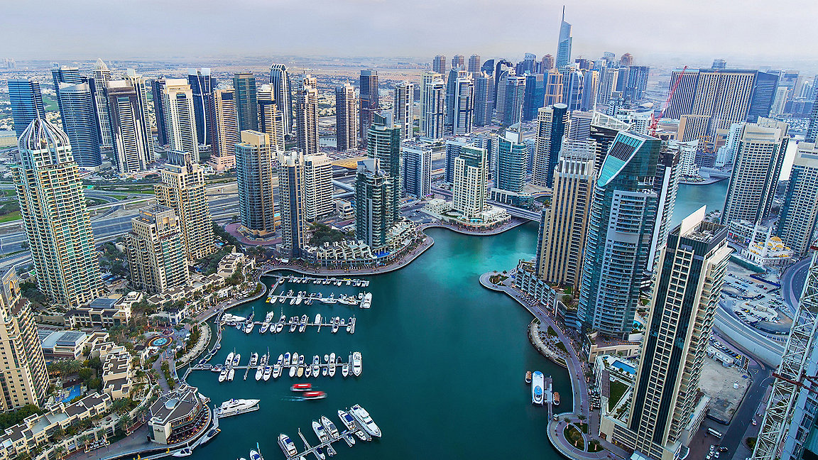 Dubai Marina - aerial view of skyscrapers around water with moored boats at bottom of the image