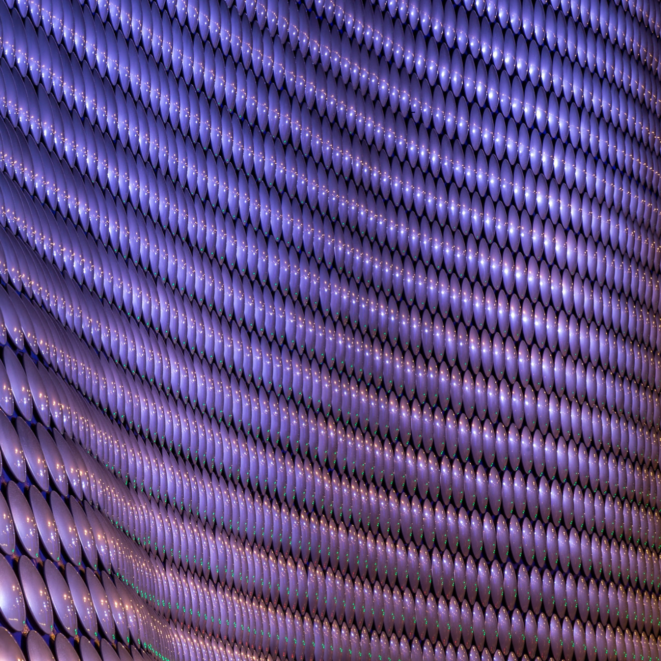 A close up of circular purple cladding on a large curved building