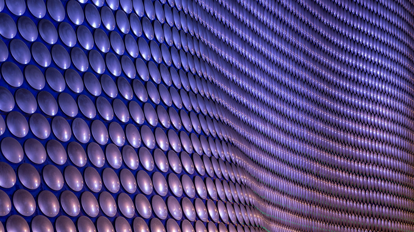 A close up of circular purple cladding on a large curved building