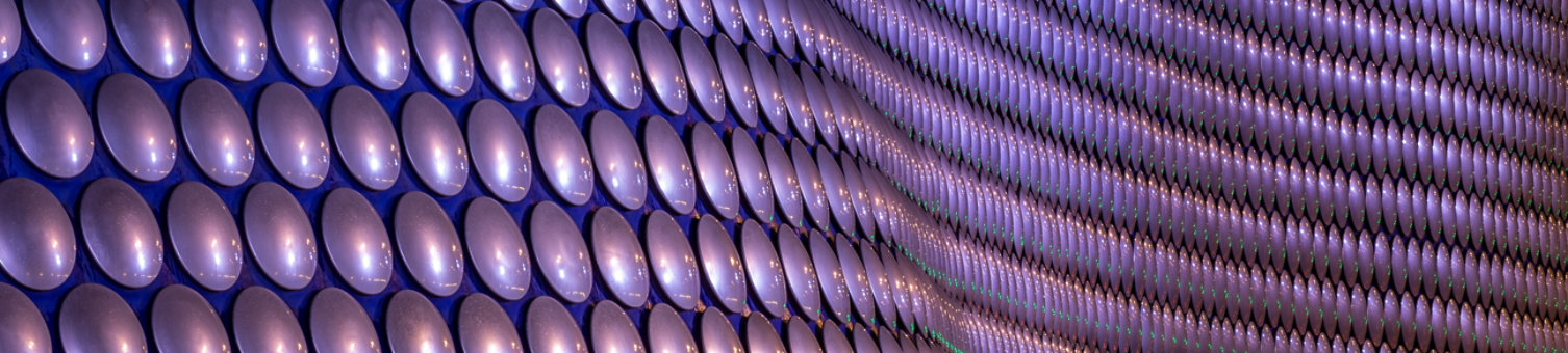 A close up of circular purple cladding on a large curved building