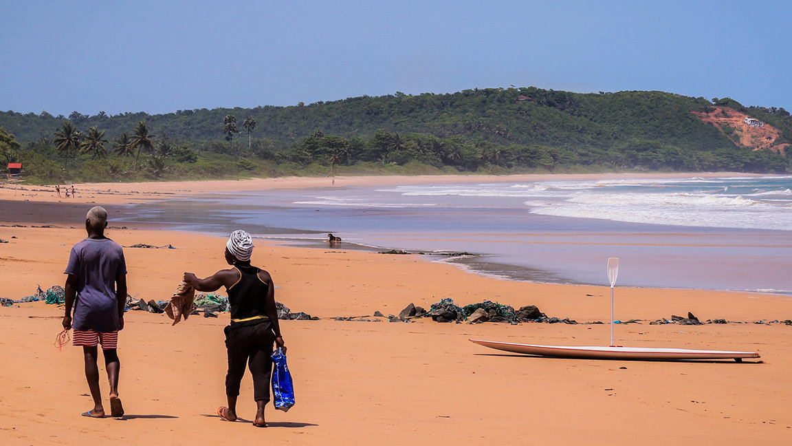 Local people walking on Axim beach, Ghana