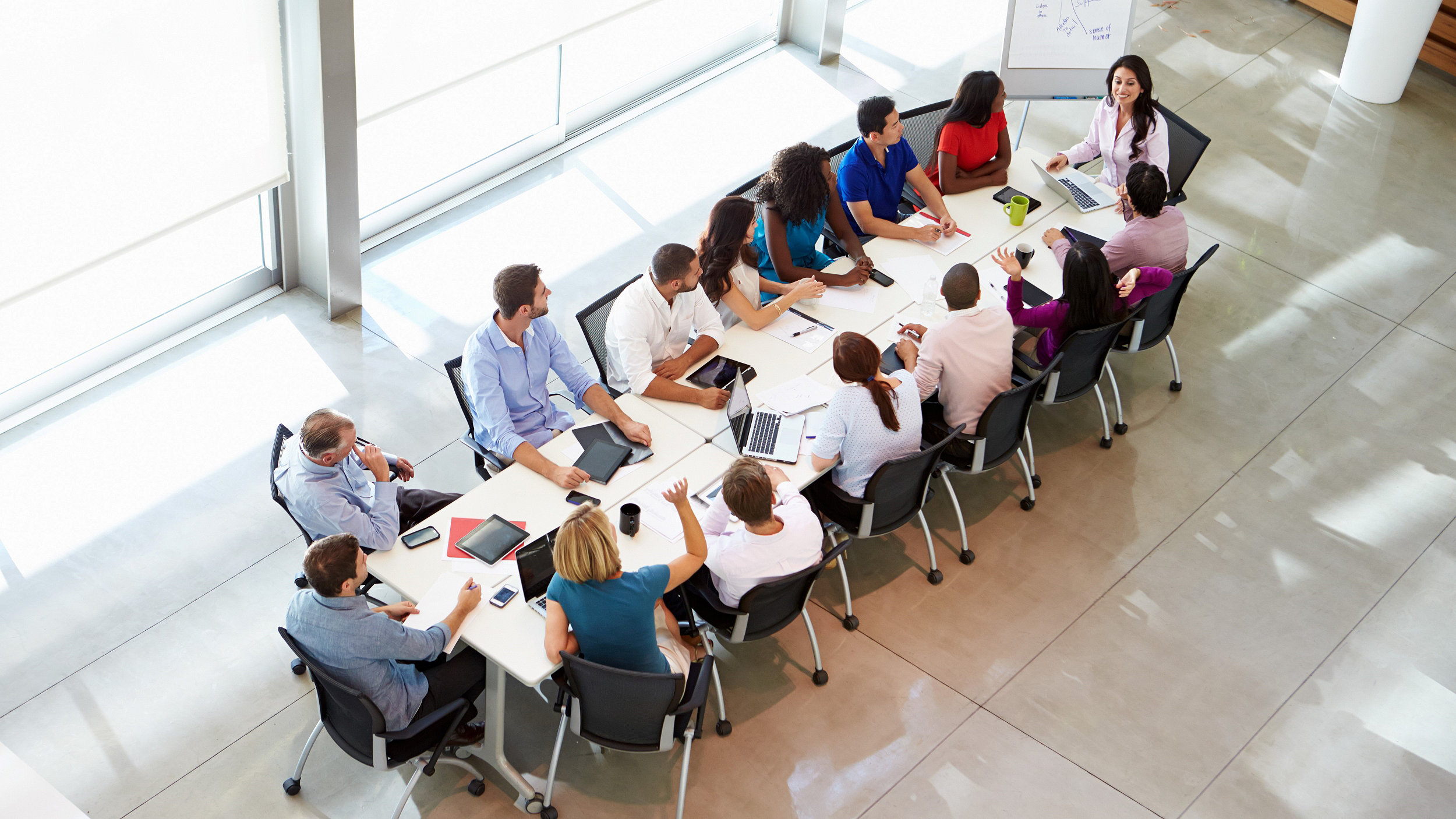 Overhead photo of business meeting with several people at long desk