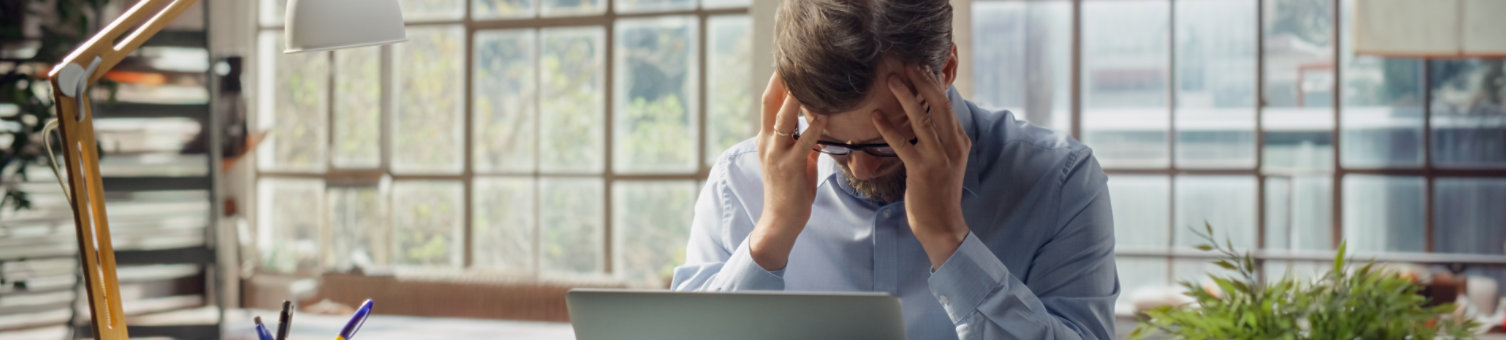Professional Displays Signs of Stress While Working on Laptop. Visual Metaphor for Workplace Pressure, Modern Struggle Between Productivity Demands and Mental Well-being in Today's Environment.