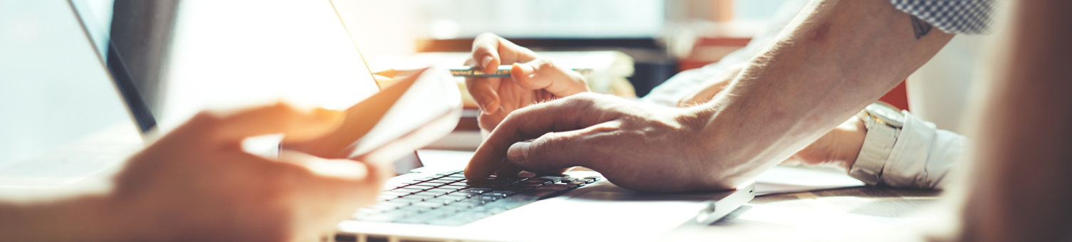 Group of young business people working together. Loft office and smart casual dress code. Researching new product strategy. Computer and paperwork. Wide screen panoramic