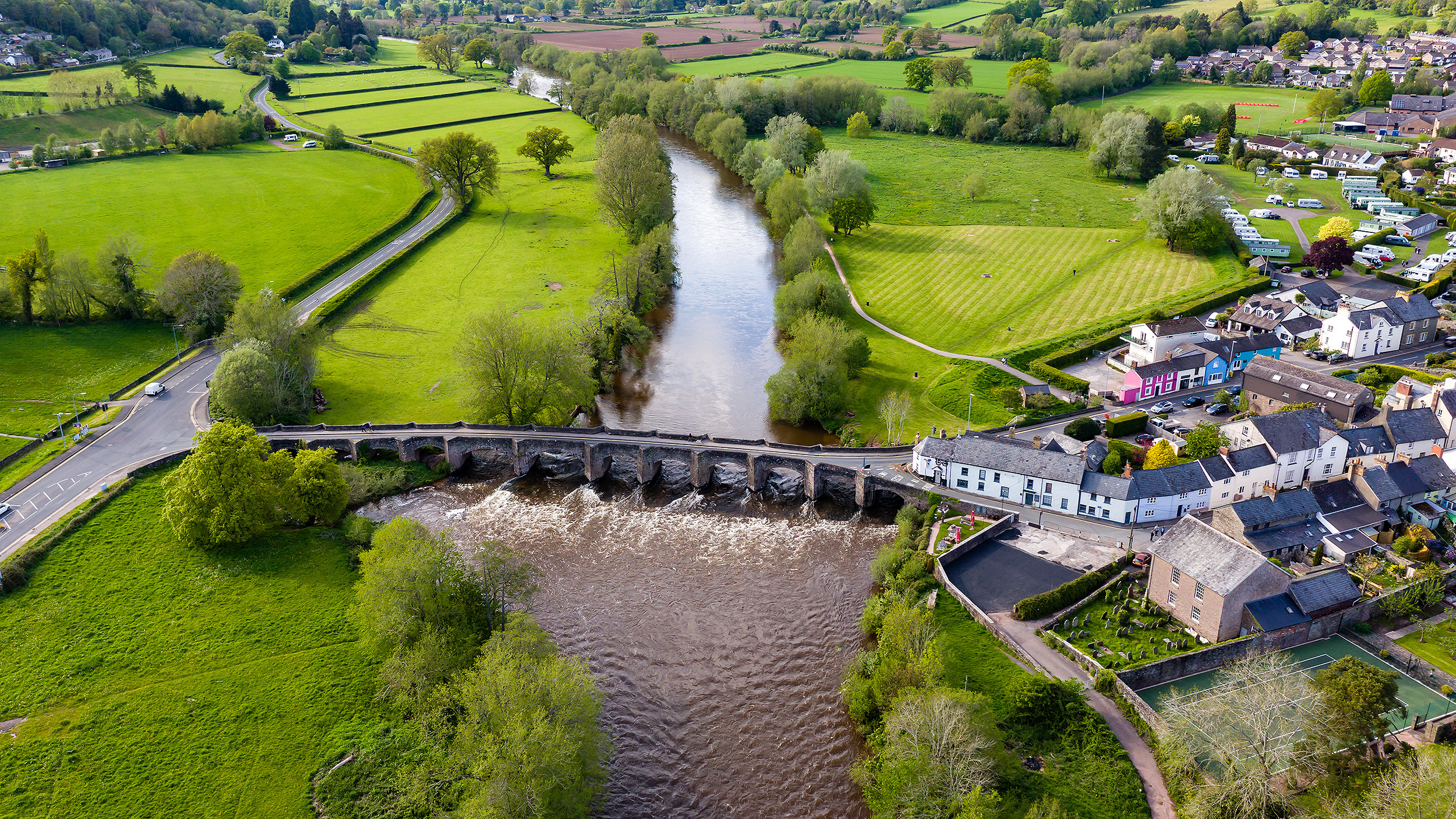 Rural village with fields, agriculture and river running through 