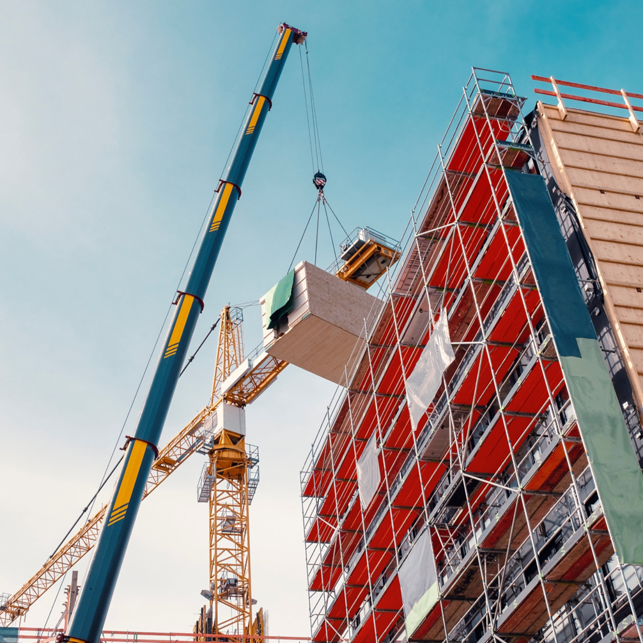 Crane lifting a wooden building module to its position in the structure. Construction site of an office building in Berlin. The new structure will be built in modular timber construction.