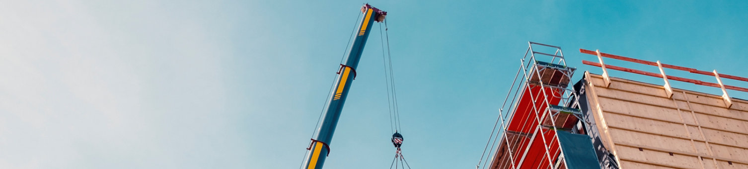 Crane lifting a wooden building module to its position in the structure. Construction site of an office building in Berlin. The new structure will be built in modular timber construction.