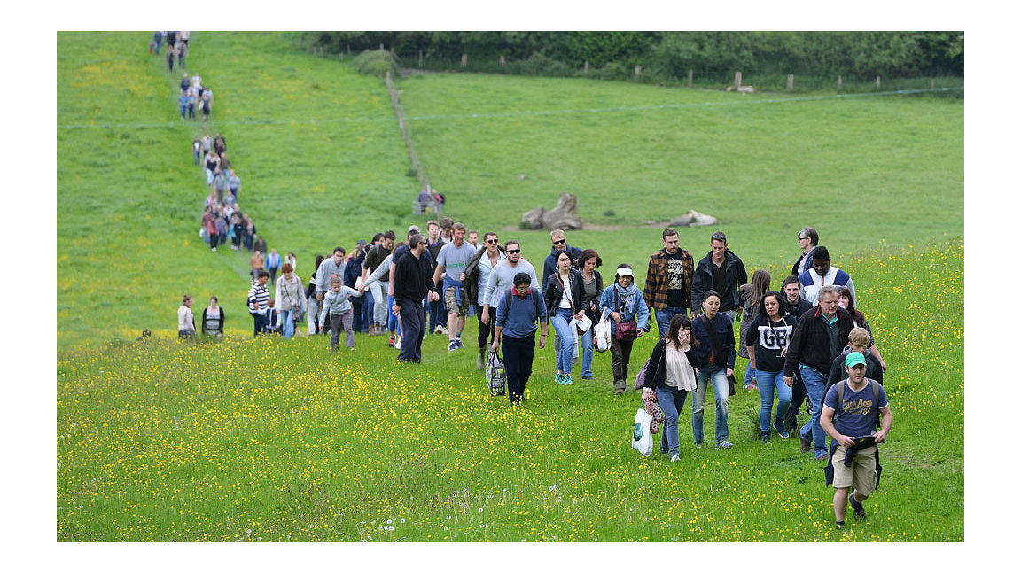 Group of people walking through a meadow up a hill