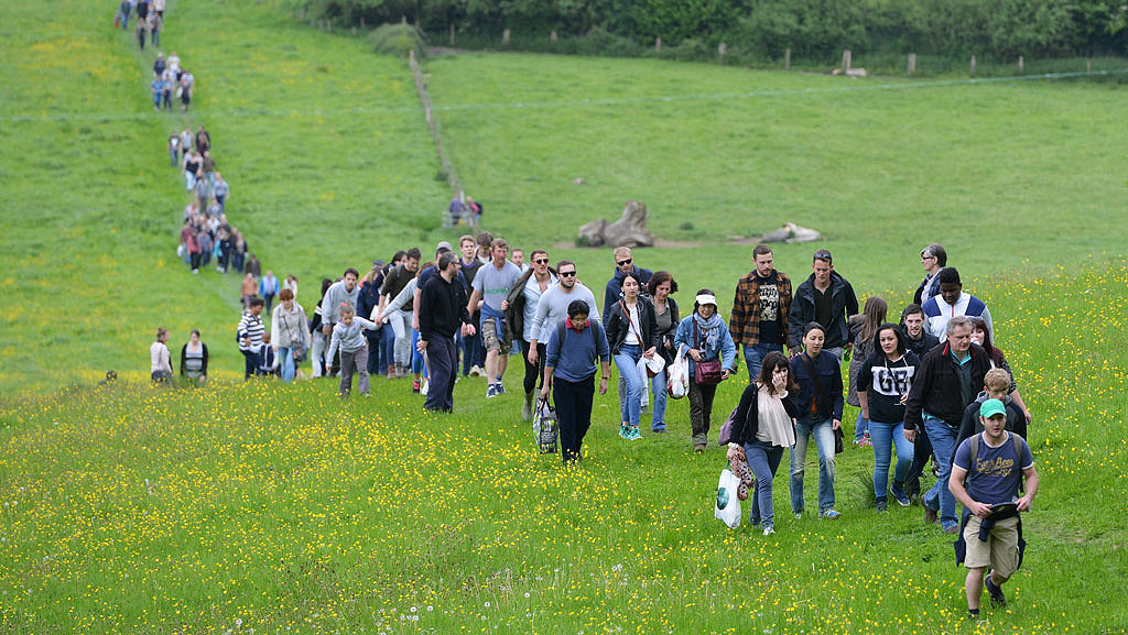 Group of people walking through a meadow up a hill