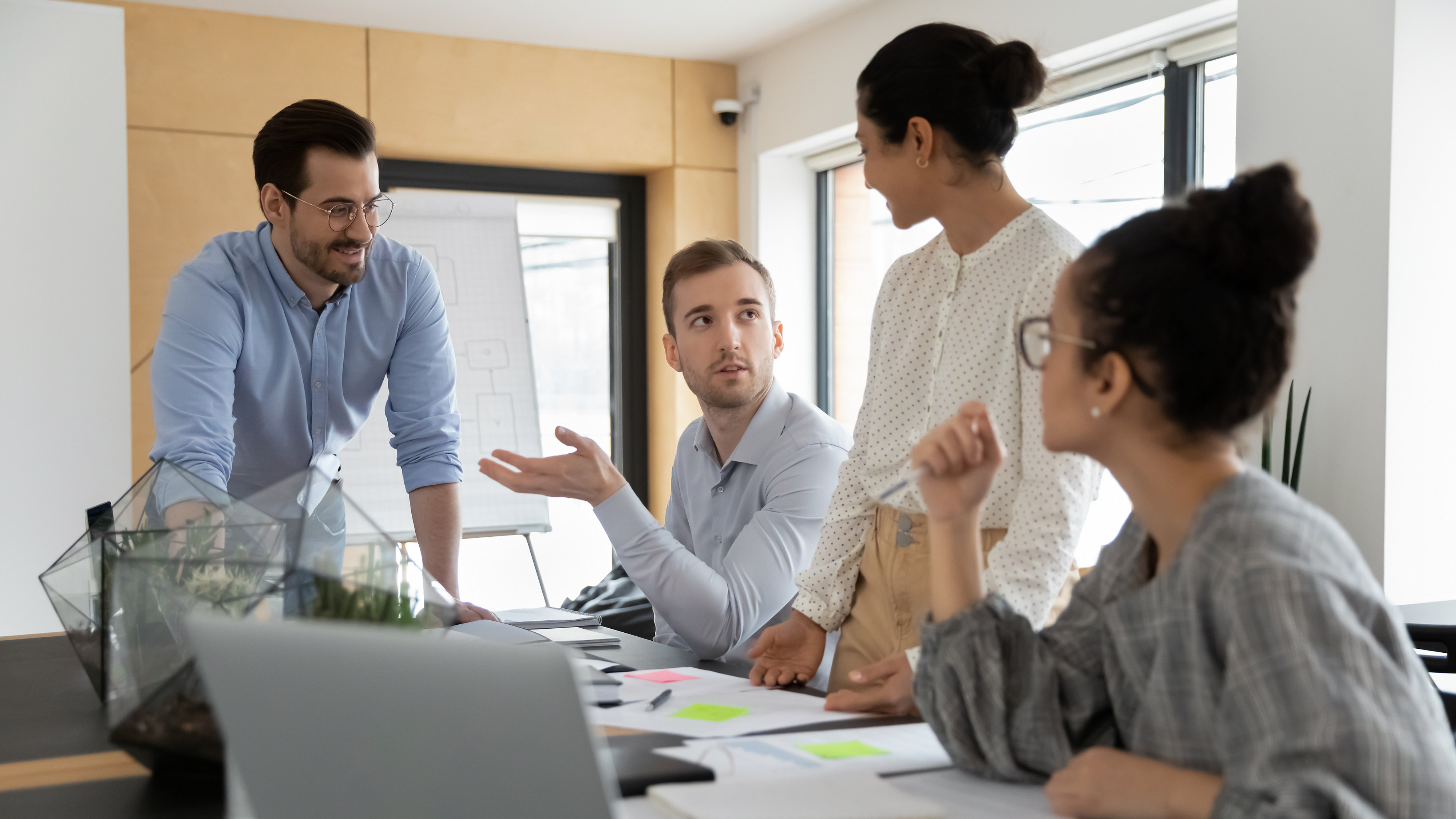 Diverse business team discussing project at corporate briefing in boardroom. Millennial colleagues meeting for brainstorming, sharing ideas, collaborating on startup together. Teamwork concept
