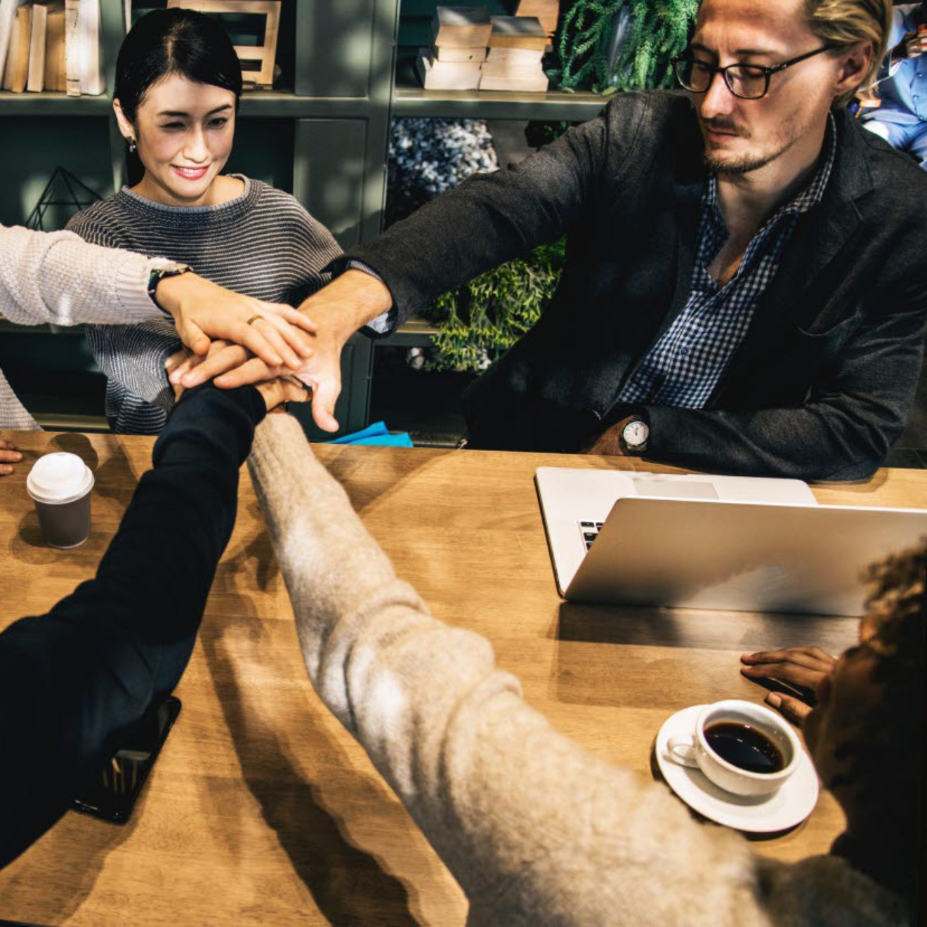 A group of young professionals placing their hands together at a table