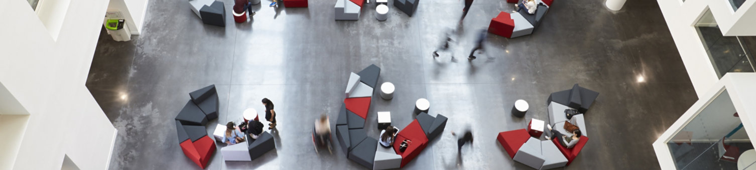 Long exposure photograph of groups of people on seating in a modern office environment viewed from above.
