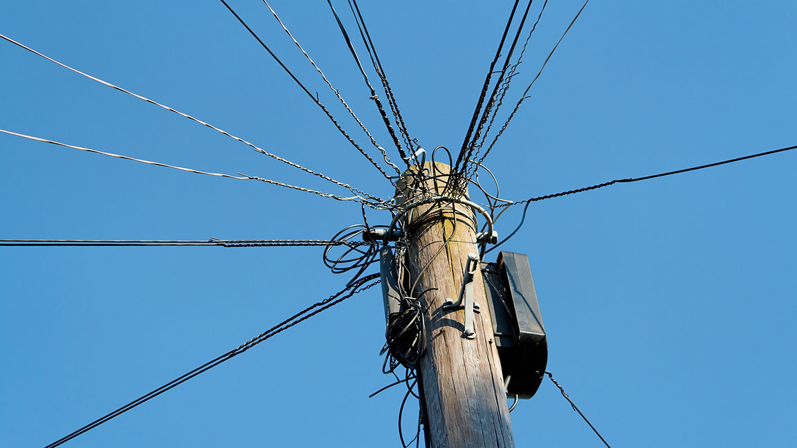 Telegraph wires against blue sky background