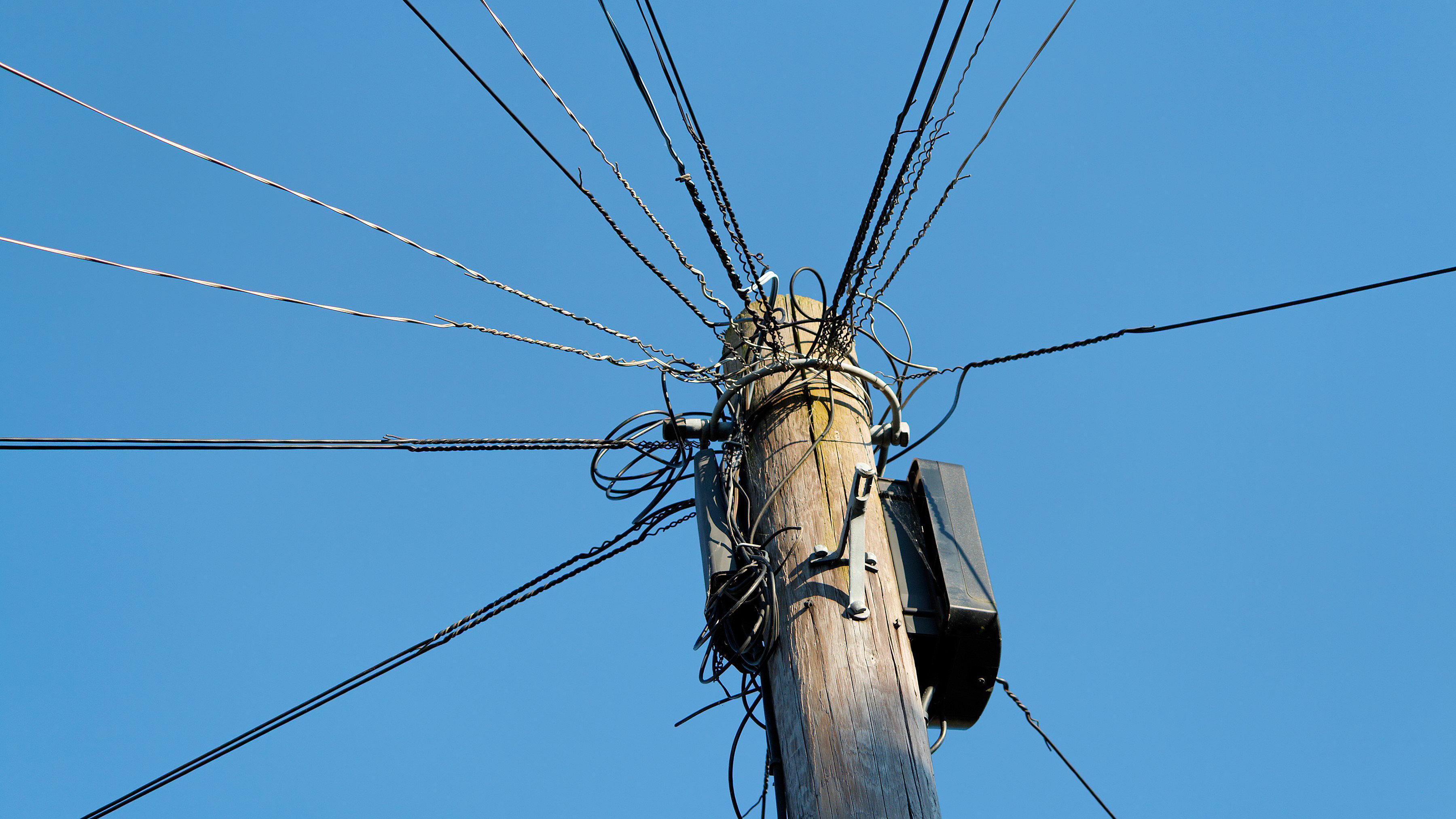 Telegraph wires against blue sky background