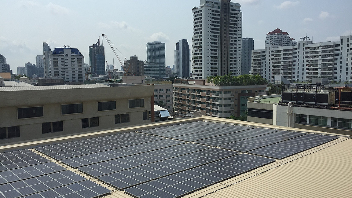 solar panels on urban building with city high rise towers in background