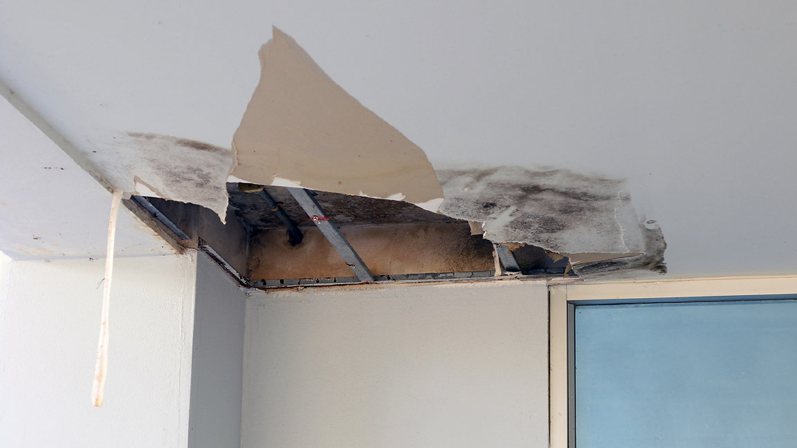 A broken office ceiling tile with evidence of damp damage