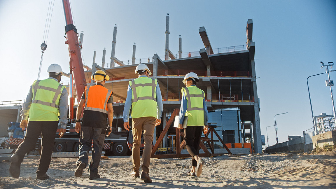 Three men and one woman walking on a construction site