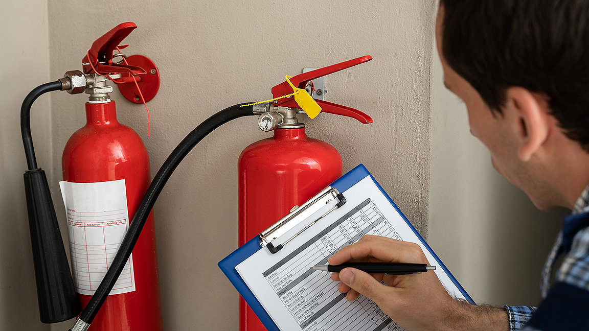 Man with checklist in front of fire extinguisher