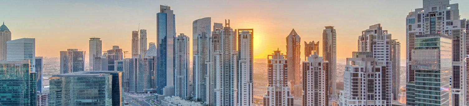 Modern residential and office complex with many towers aerial timelapse with sunset at Business Bay, Dubai, UAE. Bay Avenue Park near big parking lot with cars and traffic on roads