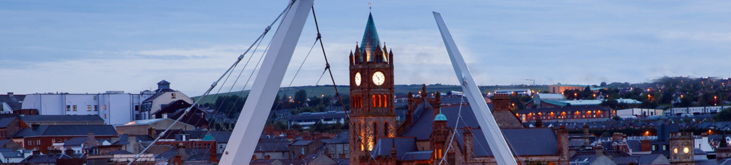 Derry, Ireland. Illuminated Peace bridge in Derry Londonderry, City of Culture, in Northern Ireland with city center at the background. Night cloudy sky with reflection in the river at the dusk