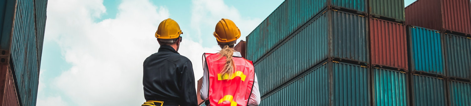 Industrial worker works with co-worker at overseas shipping container yard . Logistics supply chain management and international goods export concept .