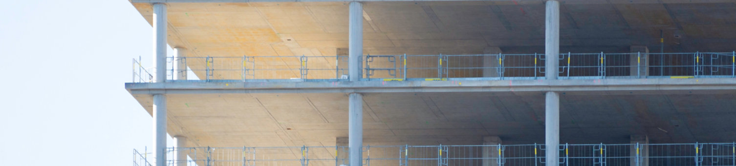The bare concrete skeleton of a new high-rise building at Alexanderplatz, Berlin. The repeating pattern of floors and columns symbolizes urban growth, real estate investment, architectural progress.