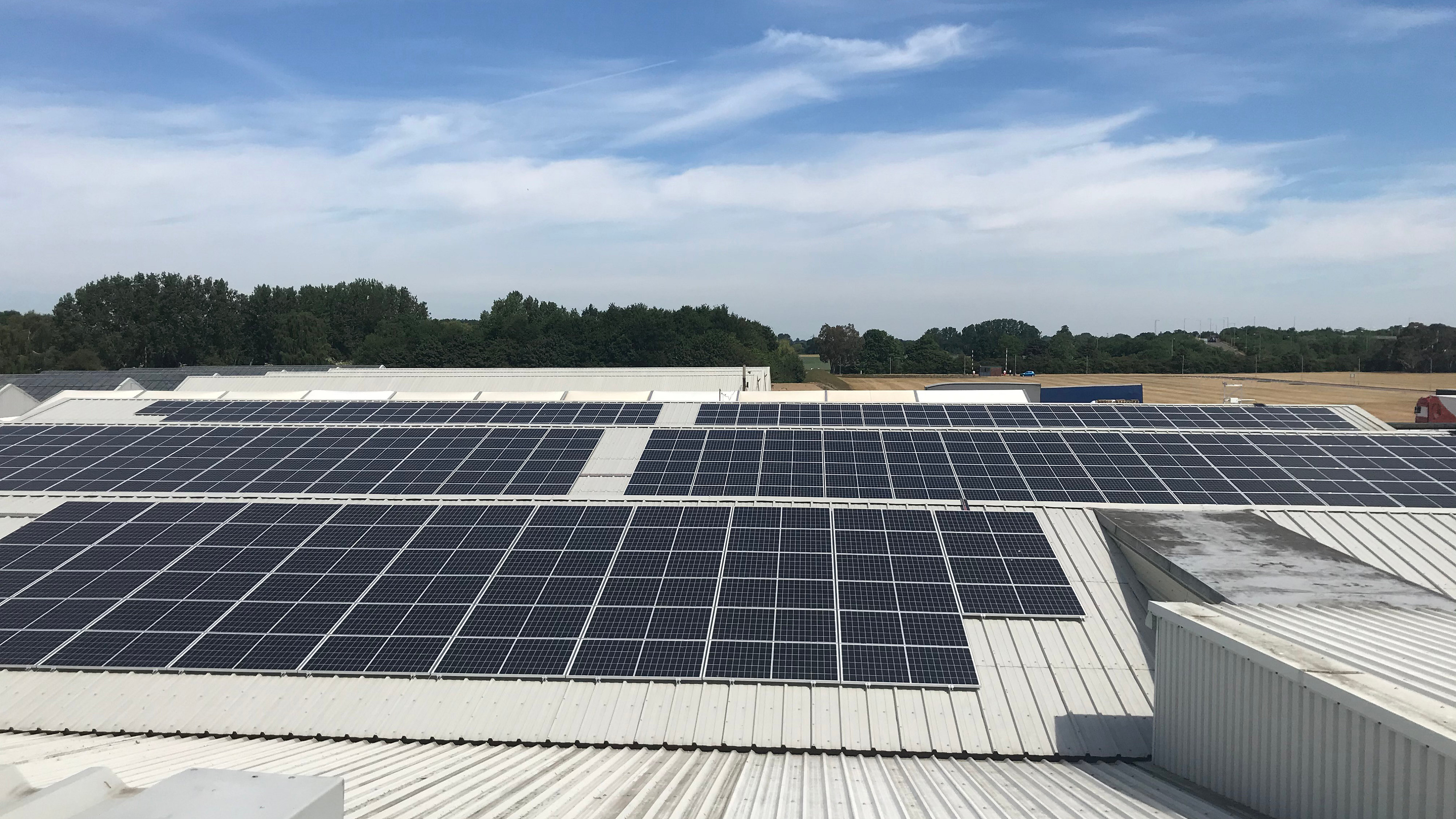 Solar panels on industrial building roof with blue sky above