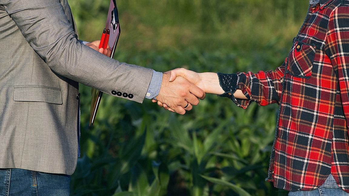 Woman farmer shaking hands with business person