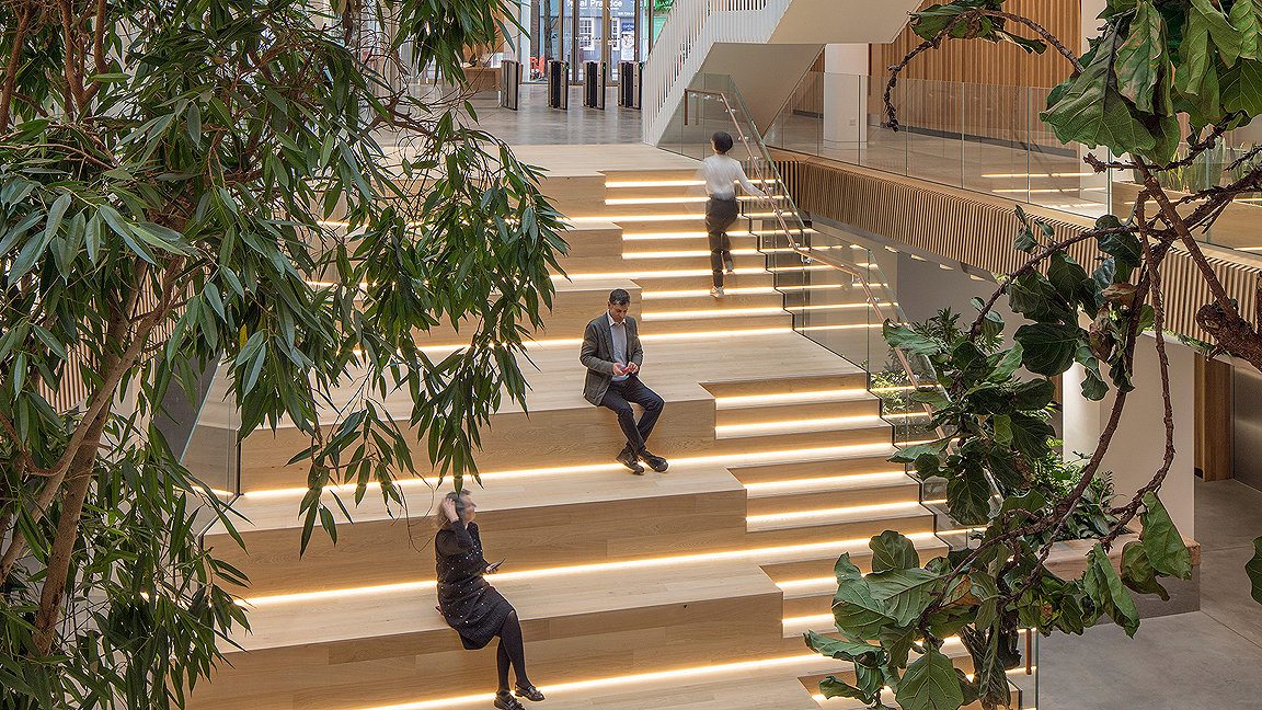 People sitting on wooden hang out stairs in office atrium