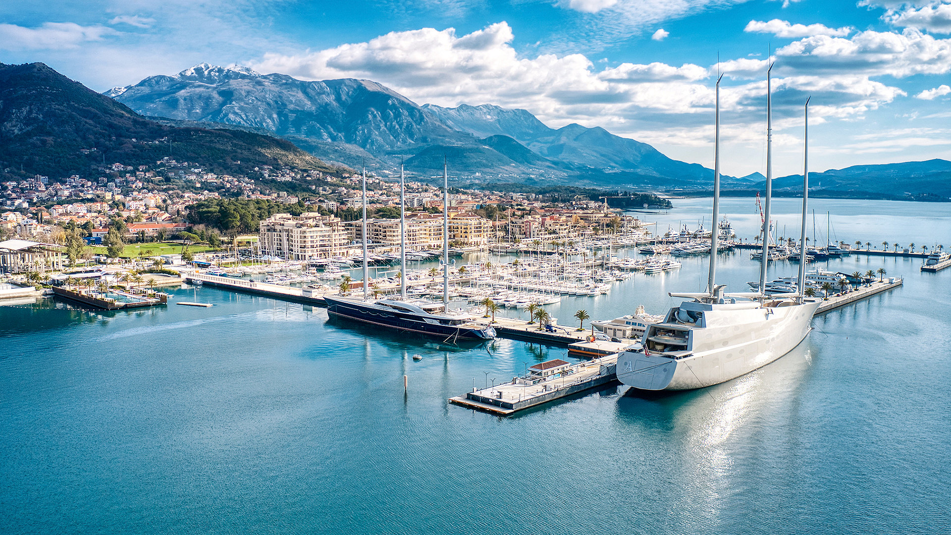 Aerial view of super yachts docked in a marina in mountain coastal town