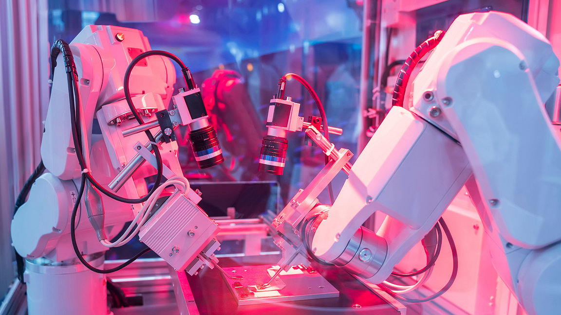 Robot arms in factory in pink hue
