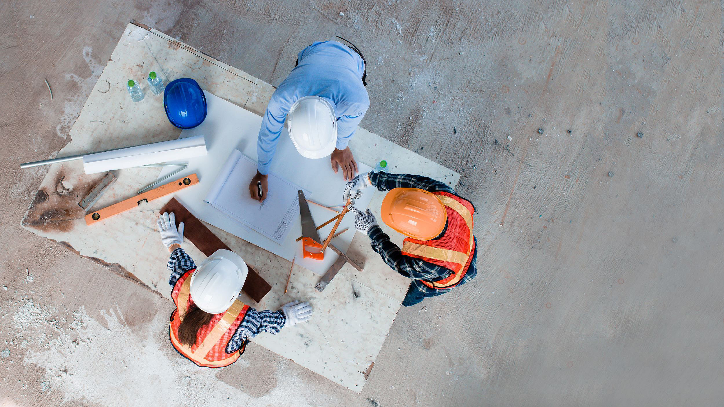 Overhead picture of people in hard hats looking at a design on paper on a table