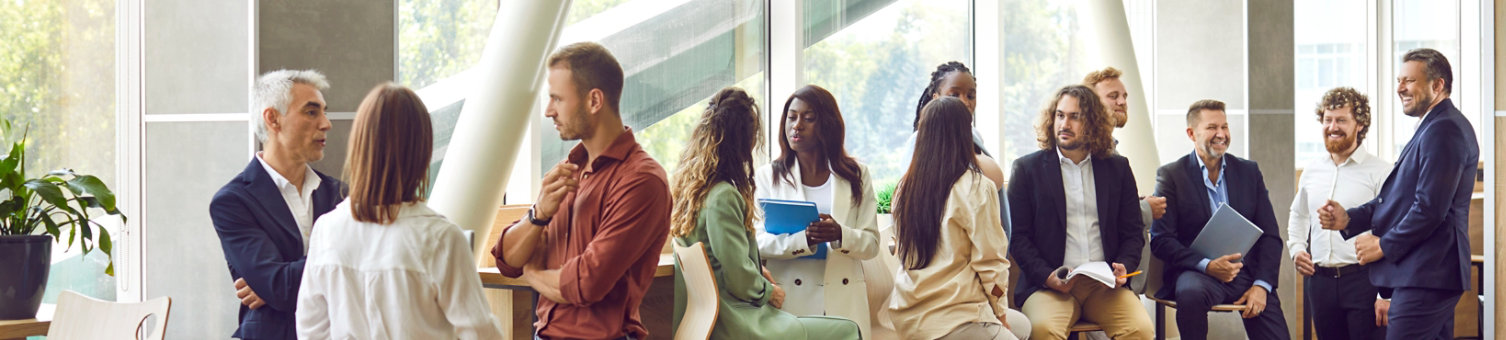 Diverse business professionals communicating at a conference, seminar or other educational event. Young and mature multiethnic people meeting in the office and having discussions. Banner background