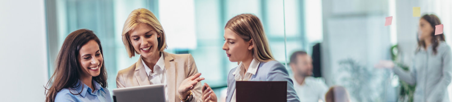 Three women chatting around an ipad