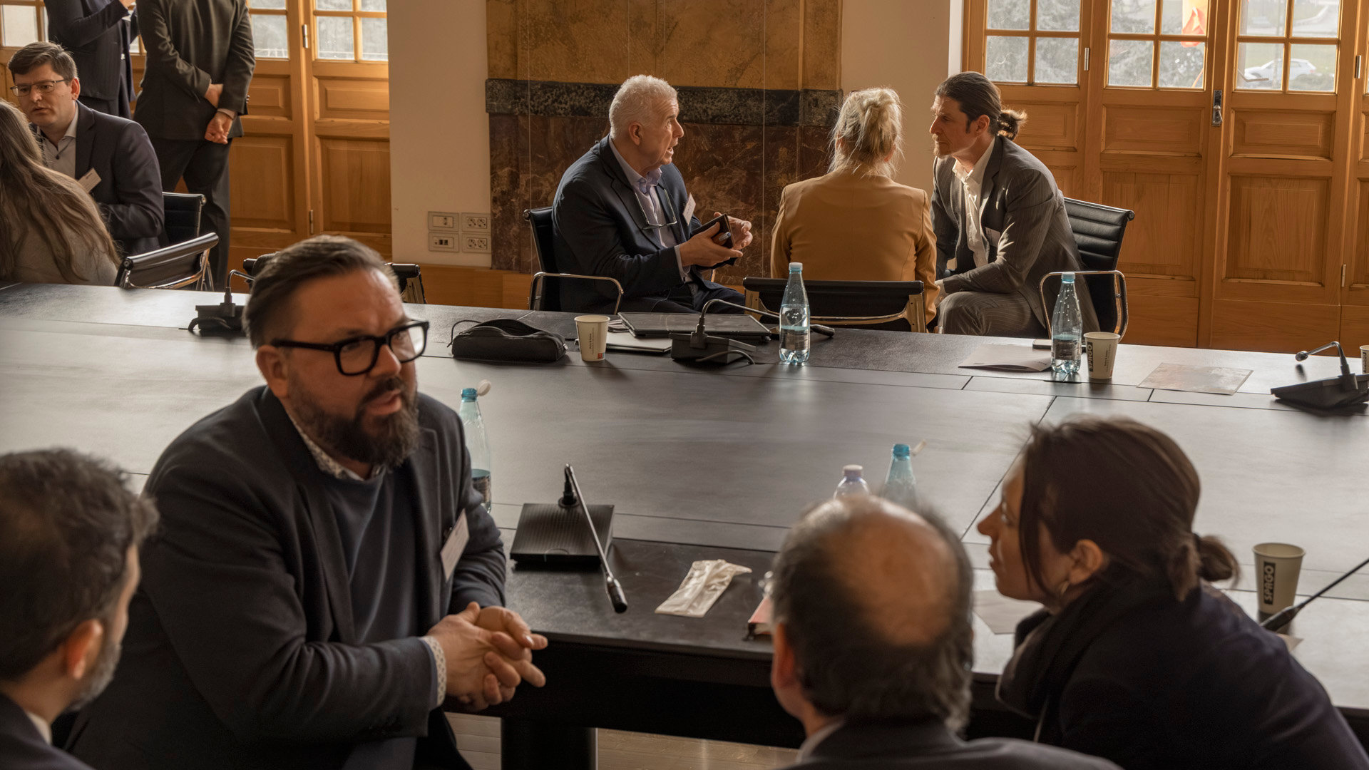 A group of attendees at the RICS European Education Forum 2026 during a discussion. Other groups are shown having discussions in the background,.