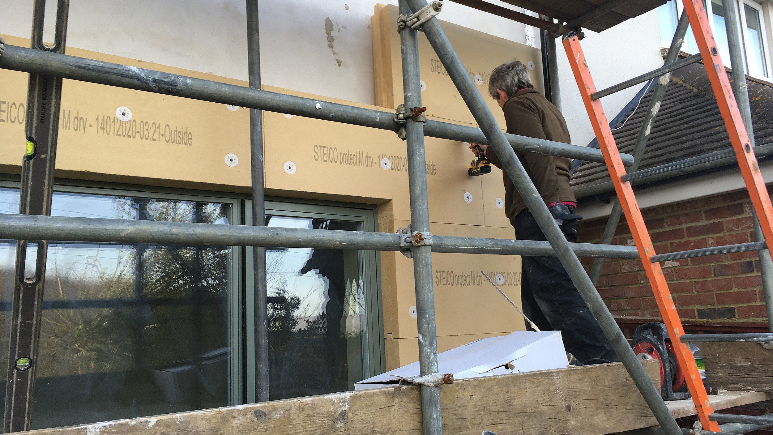 Man installing external wall insulation on a retrofit near Canterbury