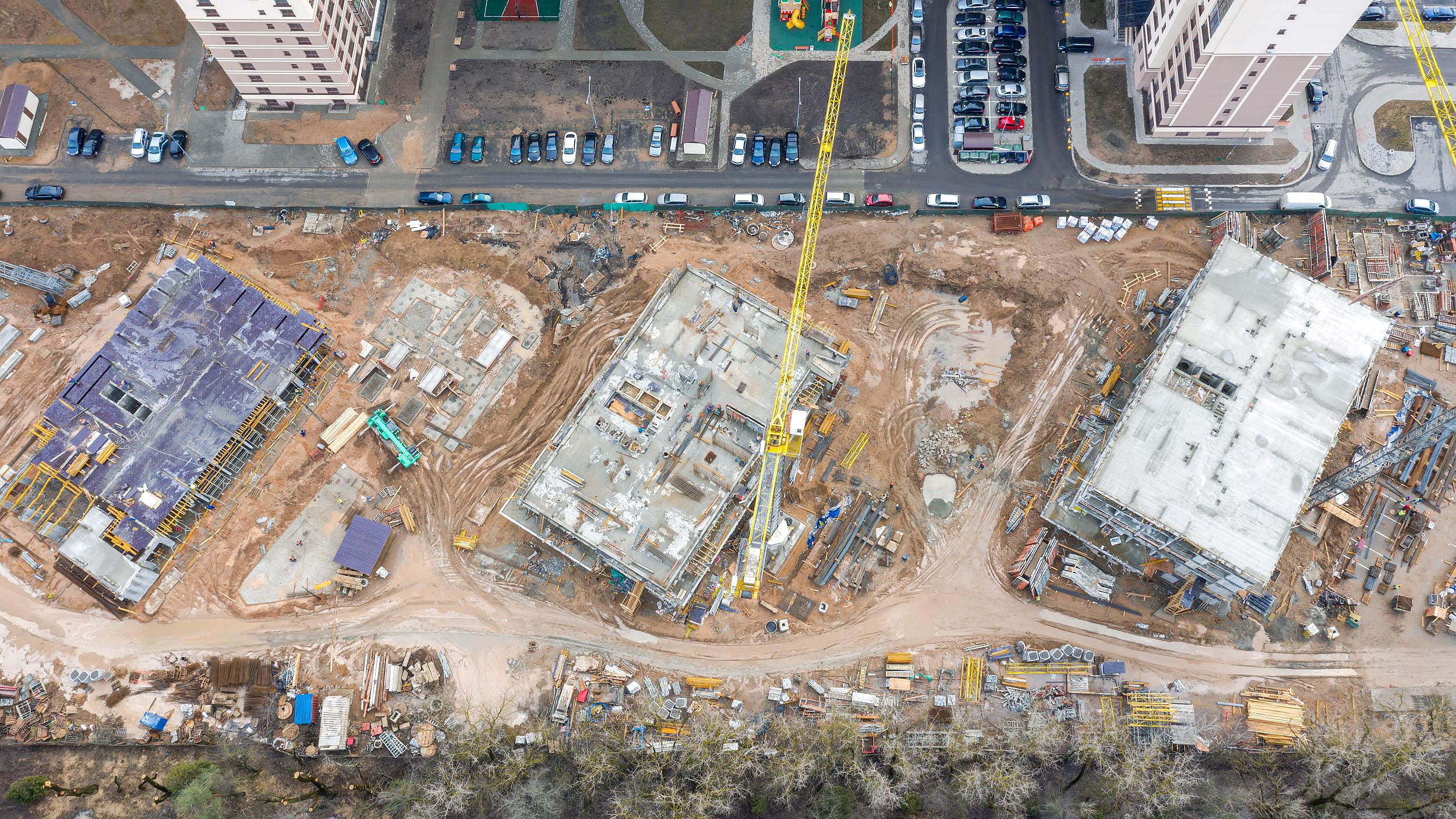 Overhead photo of buildings in various stages of construction, with a crane on site, beside finished high rises