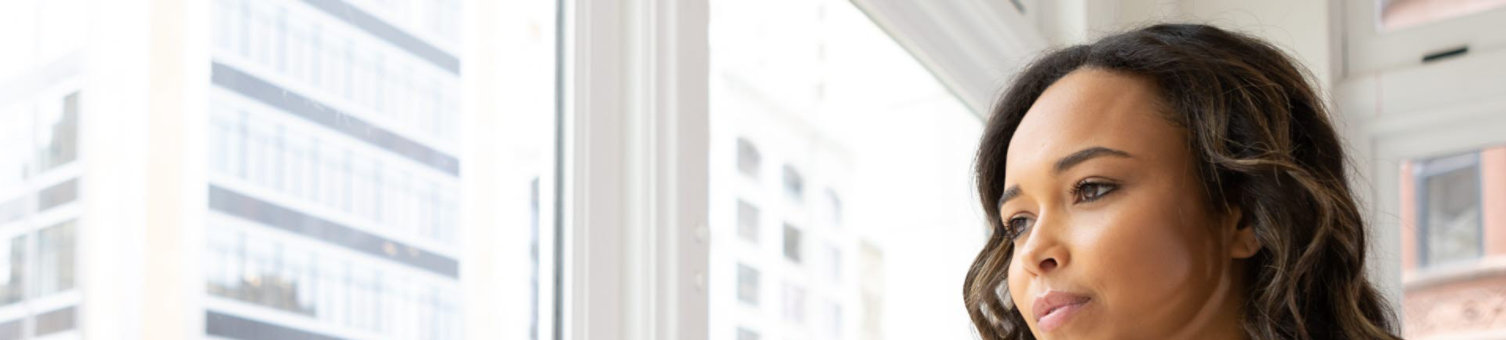 A woman looking out of an office window at the city