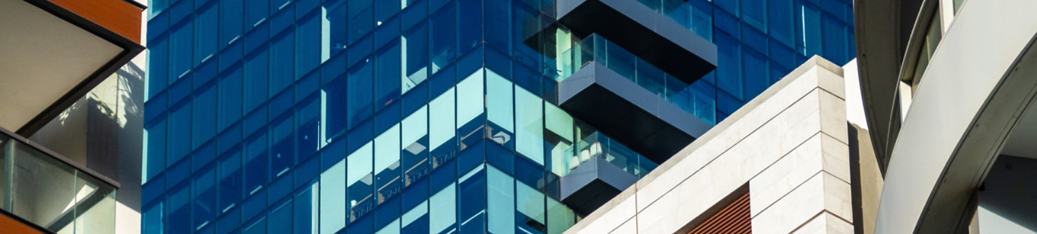 Contrasting architecture with an old building flanked by modern glass high-rises under a blue sky