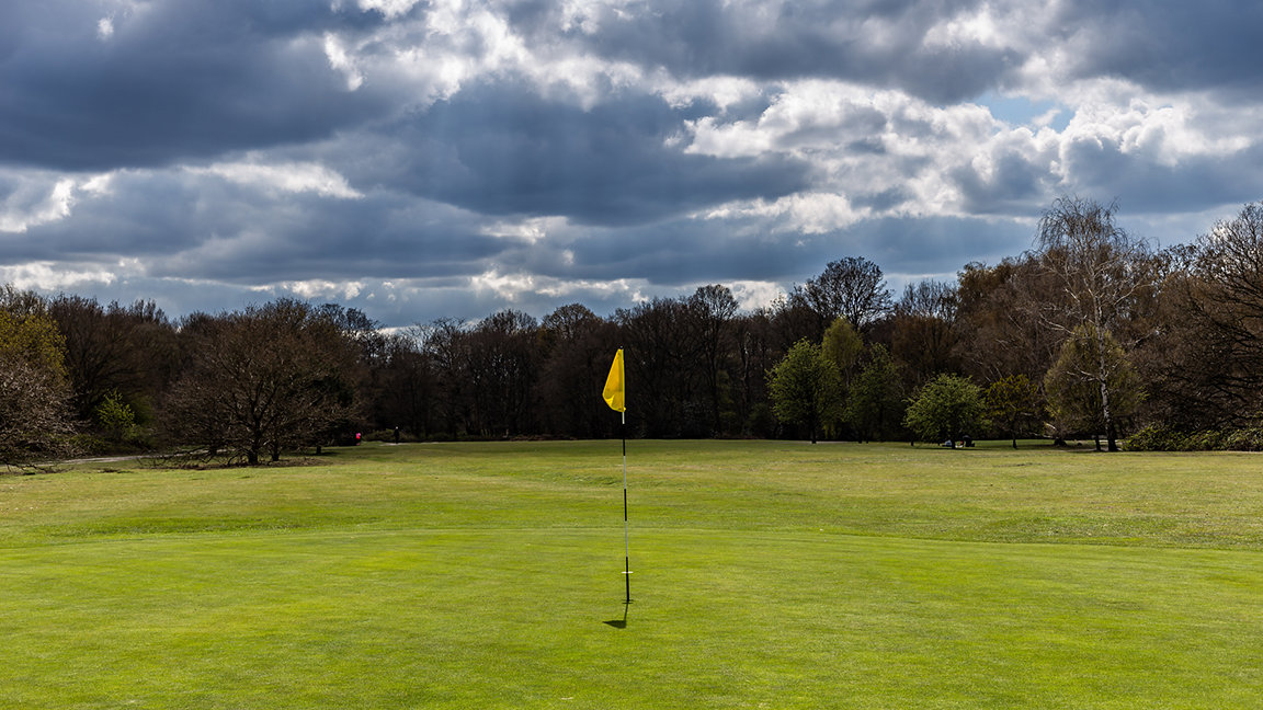 Golf flag on putting green with dark sky