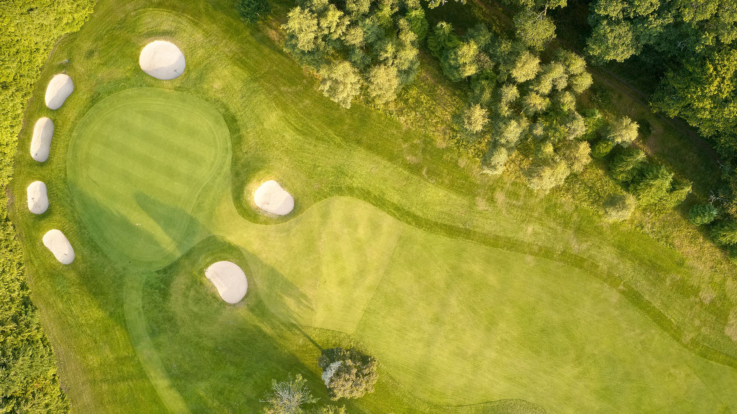 Golf course in summer showing green and bunkers at driving range