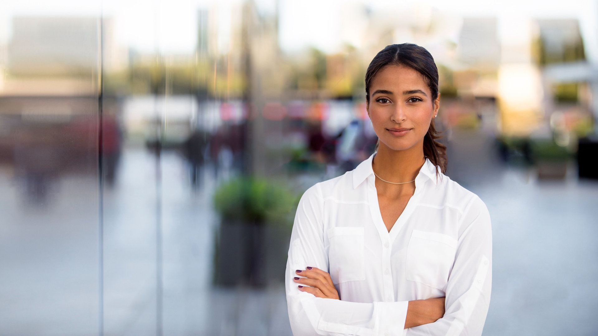 Young professional woman with crossed arms looking at the camera and smiling slightly.